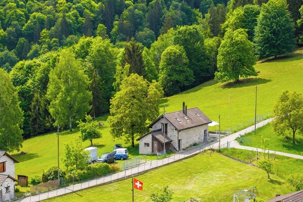 A rural landscape with a small house, a flag, and a road. - Casa Eyrie Centovalli 3BR Chalet (Centovalli)