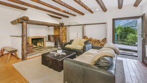 A living room with a fireplace, leather sofas, and a view of mountains.