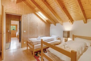 A wooden room with bunk beds, a door leading to another room, and a lamp on the wall. - Casa Eyrie Centovalli 3BR Chalet (Centovalli)