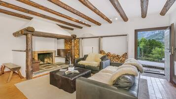 A living room with a fireplace, leather sofas, and a view of mountains.