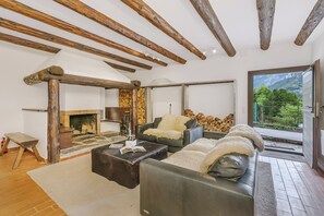 A living room with a fireplace, leather sofas, and a view of mountains. - Casa Eyrie Centovalli 3BR Chalet (Centovalli)