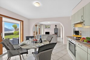 A modern kitchen with a dining area, a fireplace, and a view of the outdoors. - Panoramic Garden Lake View in Locarno Monti (Locarno)