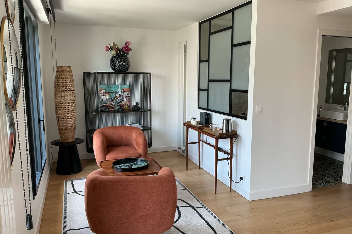 Un salon moderne avec un canapé, une table basse, un tableau et un grand vase.