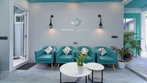 Un espace d’accueil avec des fauteuils de couleur turquoise, un comptoir de réception blanc et un logo sur le mur.