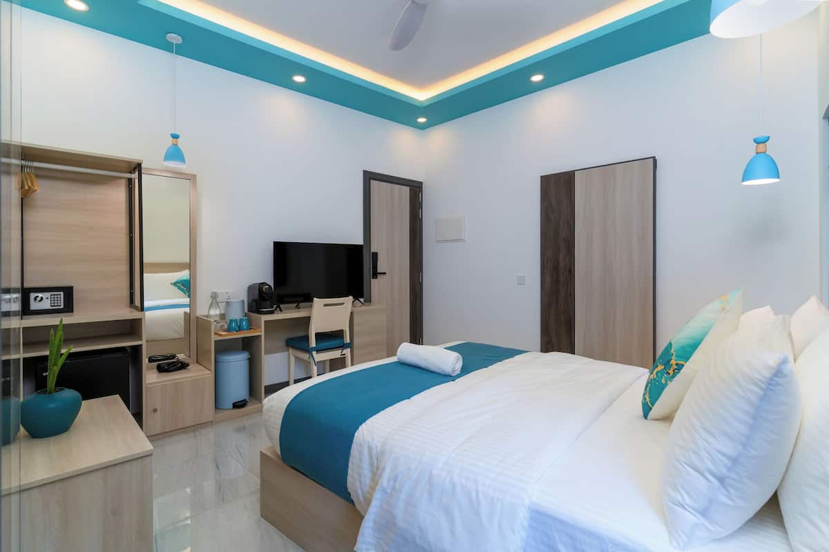 Una habitación de hotel moderna con cama, escritorio, televisor y armario.