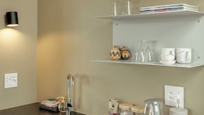 Een keuken met een granieten aanrecht, een roestvrijstalen spoelbak en witte planken erboven.