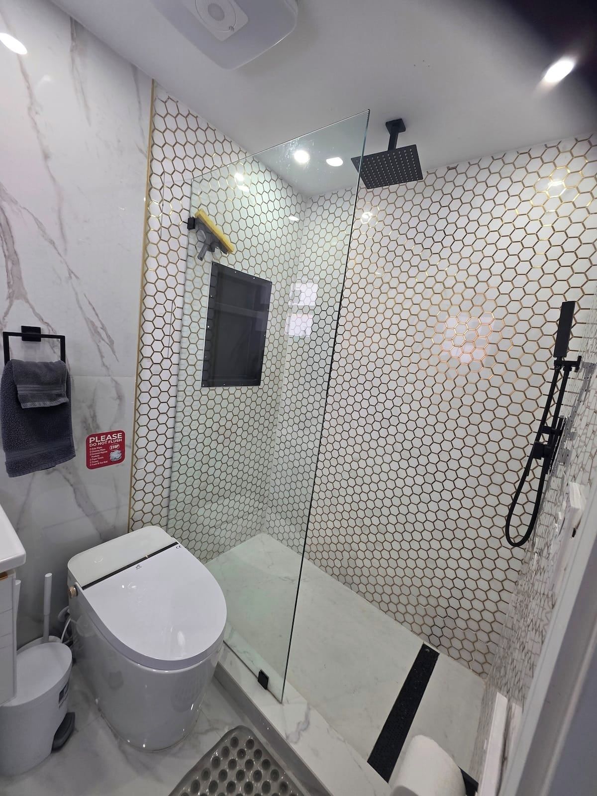 Un baño moderno con ducha de vidrio, inodoro y lavamanos.