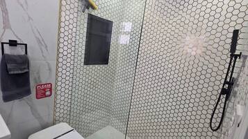 Un baño moderno con ducha de vidrio, inodoro y lavamanos.