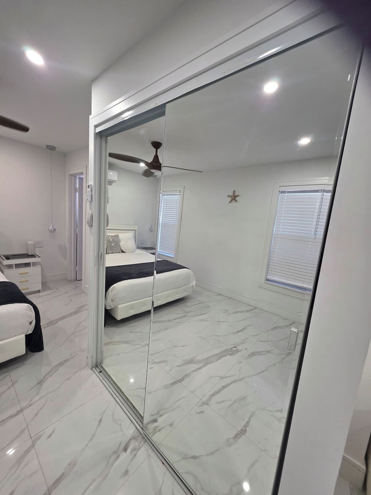 A bedroom with a bed, a wardrobe, a ceiling fan, and a window with blinds.
