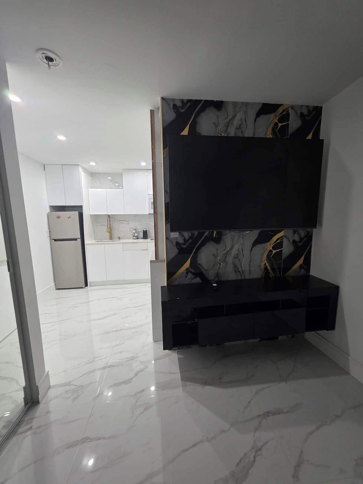 A modern kitchen with white cabinetry, a built-in oven, and a black countertop with a marble-like backsplash.