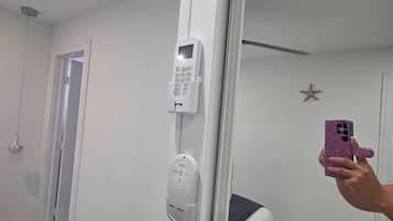 Een hotelkamer met een bed, een nachtkastje, een spiegel en een deur naar een andere kamer.