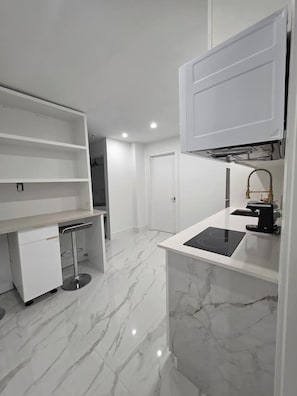 Una cocina moderna con armarios blancos, estufa integrada y encimera de mármol.