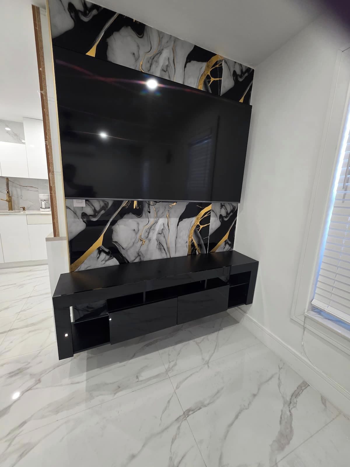 A modern living room with a large flat-screen TV mounted on a wall with a marble-like design.
