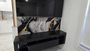 A modern living room with a large flat-screen TV mounted on a wall with a marble-like design.