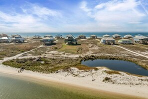 Eine Küstenlandschaft mit Strandhäusern, einem kleinen Teich und freiem Blick auf den Ozean.
