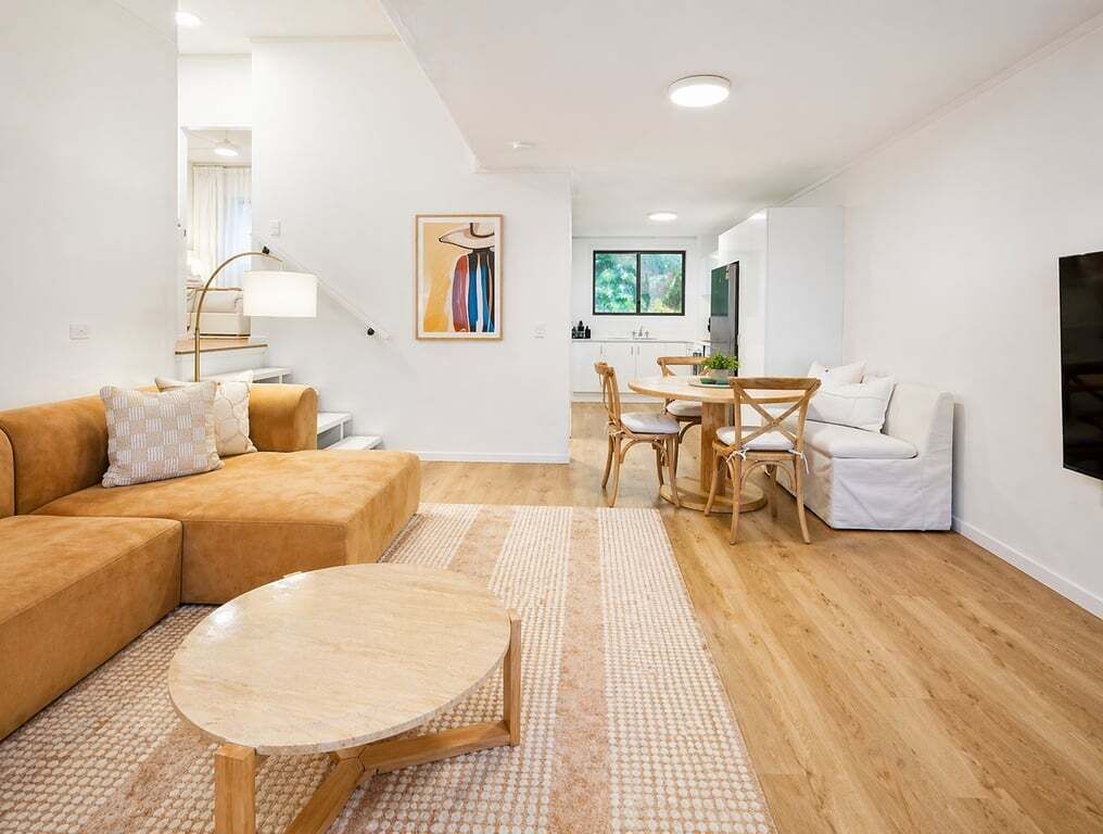 A modern living room with a sofa, round coffee table, and dining area with chairs and a table.