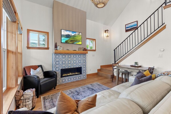 Ein Wohnzimmer mit Kamin, einer Couch, einem Fernseher und einer Treppe.
