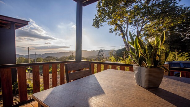 A wooden table with a potted plant on a balcony with a view of the landscape. - Los Lirios 2 Cabin (Monteverde)