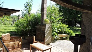 An outdoor patio with wooden furniture, a stone fireplace, and a grill.