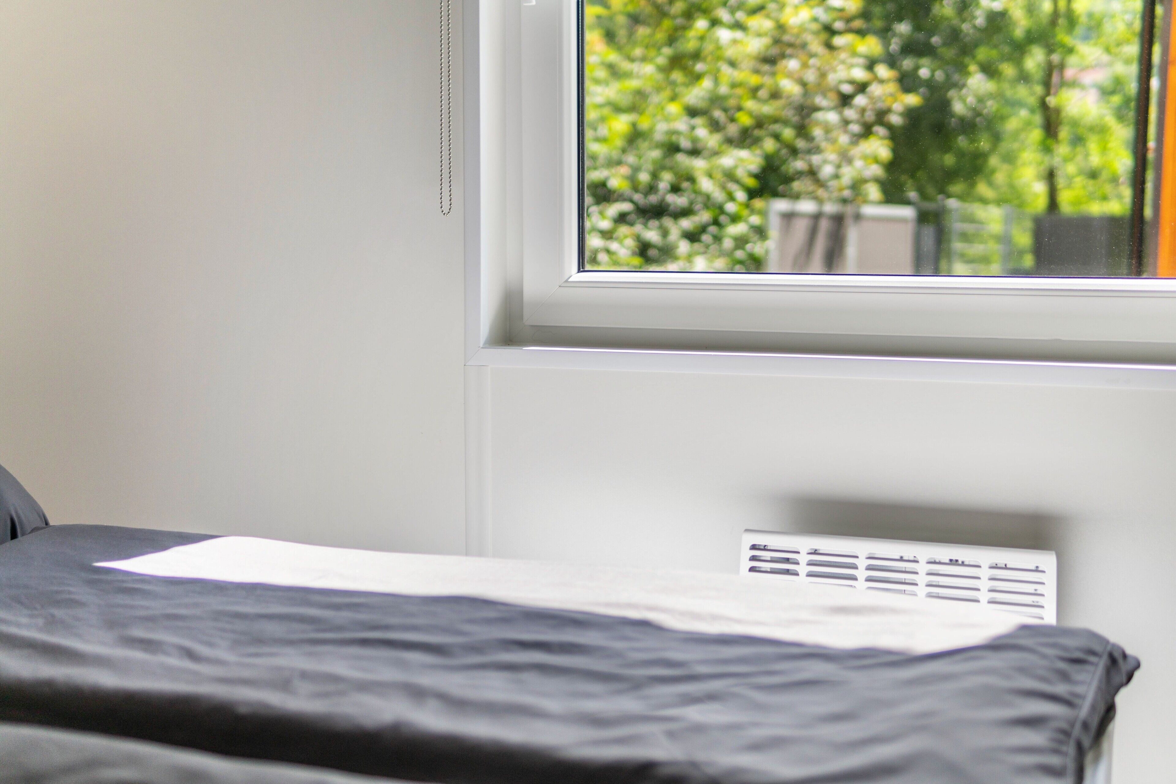 Ein Schlafzimmer mit Fenster, Bett und weißer Wand.