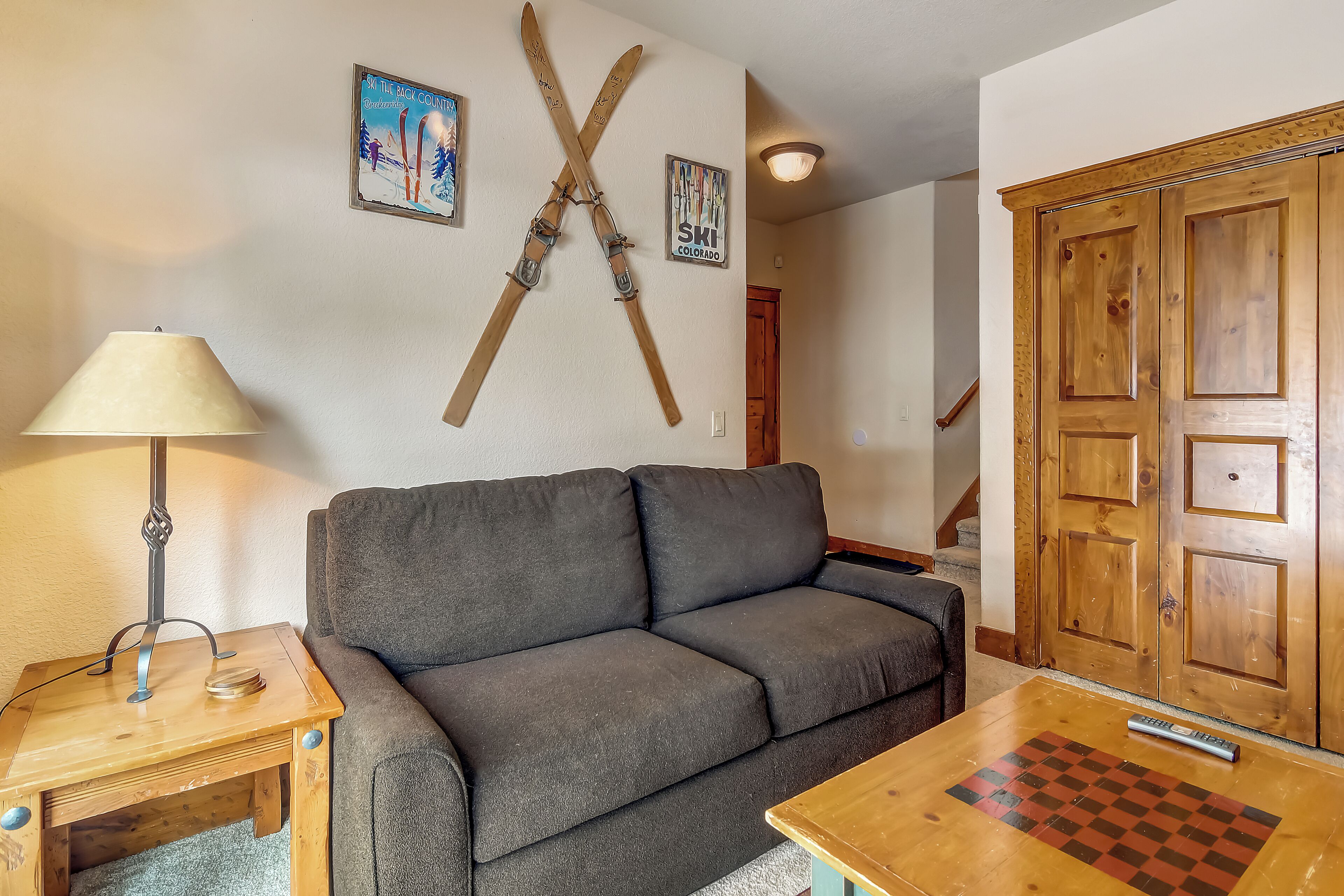 Un soggiorno con divano, un tavolo di legno con una lampada, una scacchiera e porte in legno.