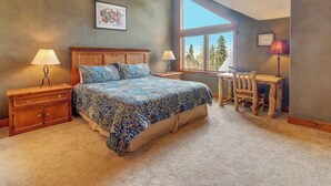 Une chambre à coucher comprenant un lit, des tables de chevet, un bureau et une chaise.