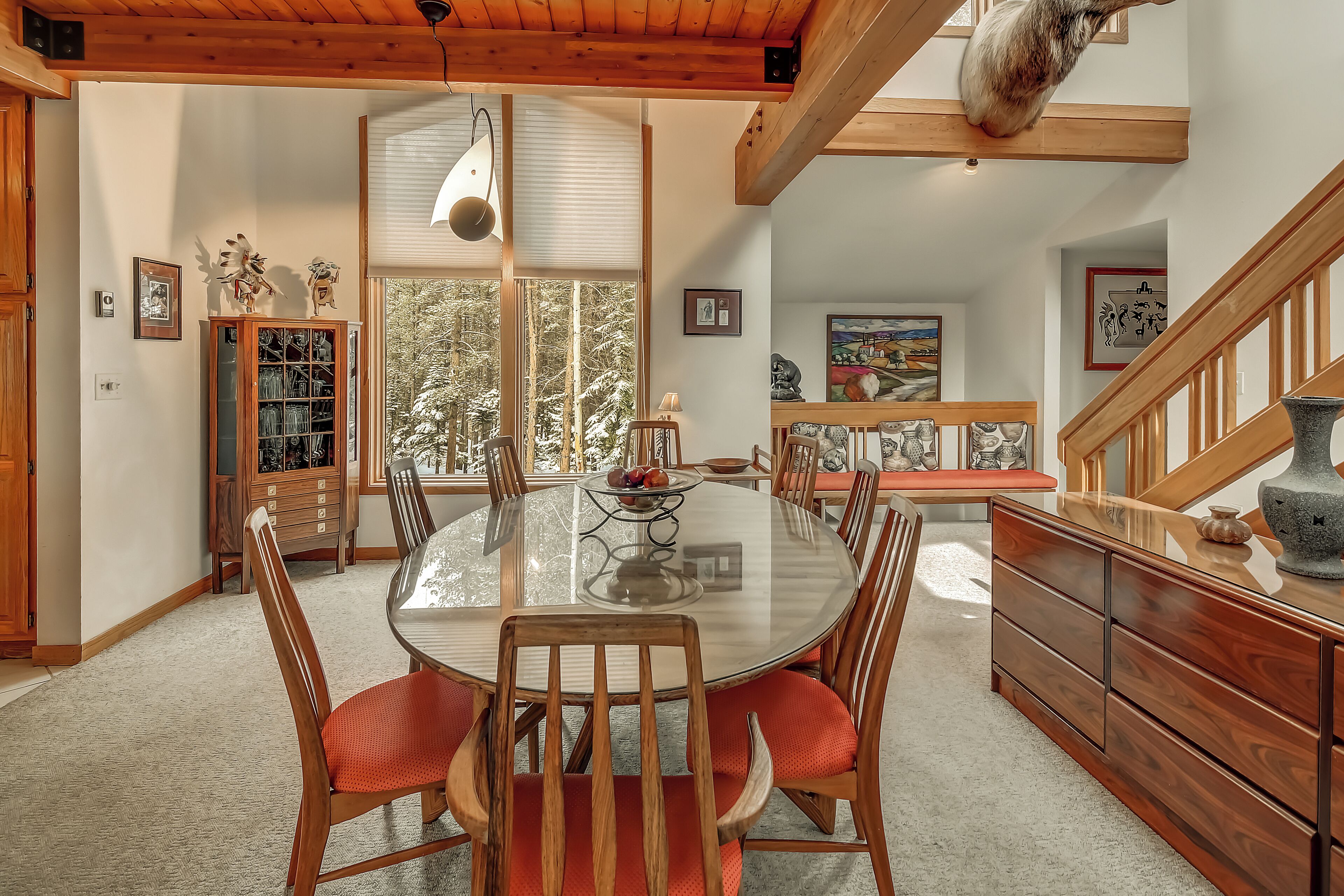A dining room with a round glass table, wooden chairs, and a bench.