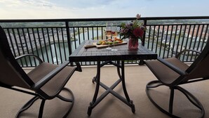A balcony with a table set for two, overlooking a body of water and a residential area. - 3BR- 9th floor- Lake & Golf View condo|Short walk to beach| Resort Access| (North Myrtle Beach)