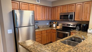 A kitchen with wooden cabinets, a stainless steel refrigerator, a microwave, an oven, and a granite countertop. - 3BR- 9th floor- Lake & Golf View condo|Short walk to beach| Resort Access| (North Myrtle Beach)