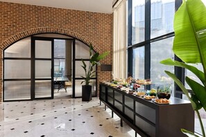 Eine großzügige Lobby mit Backsteinwand, großen Fenstern, einem Marmorboden und einem Buffet.