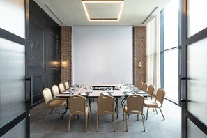 A conference room with a long table, chairs, a projector screen, and a brick wall. - Bomonti Suites (Istanbul)