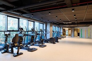 Ein Fitnessstudio mit Trainingsgeräten, großen Fenstern und einem modernen Interieur.