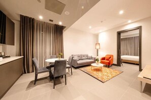 A modern hotel room with a dining area, a sofa, an orange armchair, a bed, and a large mirror. - Bomonti Suites (Istanbul)