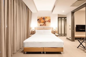 Une chambre d’hôtel avec un grand lit, un tableau au mur et un téléviseur sur le mur opposé.