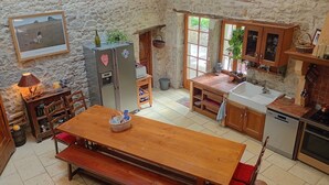 Une cuisine rustique avec une table en bois, un réfrigérateur et un évier.