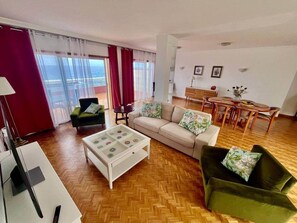A living room with a sofa, armchair, coffee table, and a dining area with a table and chairs. - Seaview Muelle en pleno centro, Puerto de la Cruz (Puerto de la Cruz)