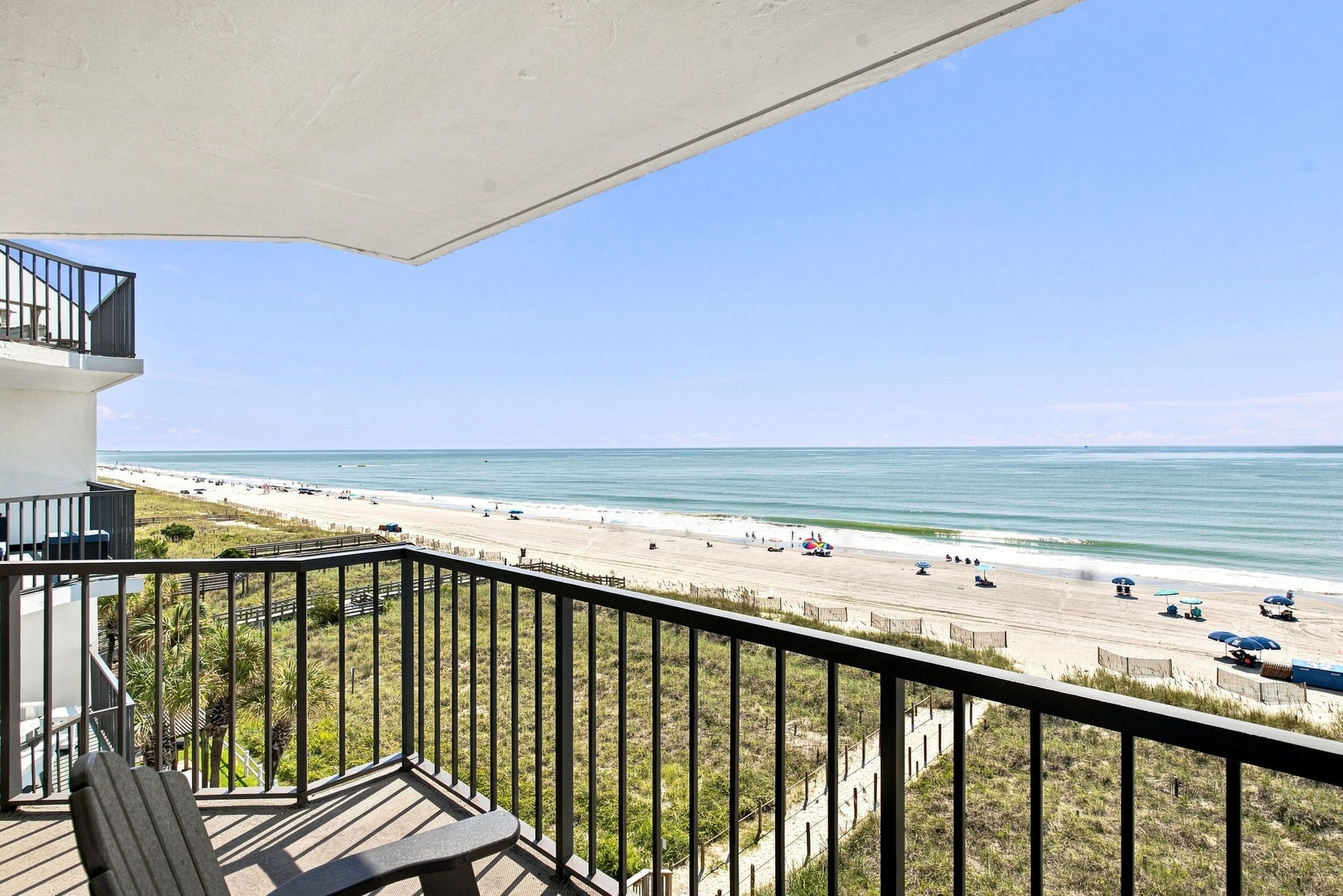 Un balcon avec vue sur une plage et l’océan.