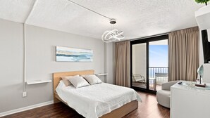 Een moderne slaapkamer met een bed, een plafondlamp, een schilderij en uitzicht op het omliggende landschap.