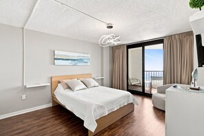 A modern bedroom with a bed, a ceiling light, a painting, and a view of the outdoors. - Beautifully Upgraded!  Pool and Beach Access (North Myrtle Beach)