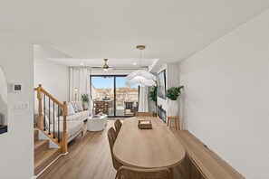 Ein großzügiger Wohnbereich mit einem Holzessttisch, einer Couch und einer Treppe zu einer oberen Etage.