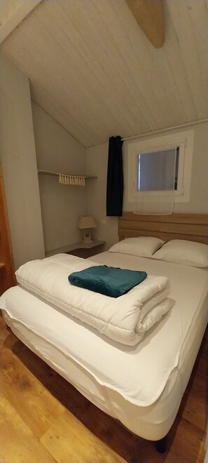 A bedroom with a bed, a window, a nightstand, and a lamp.