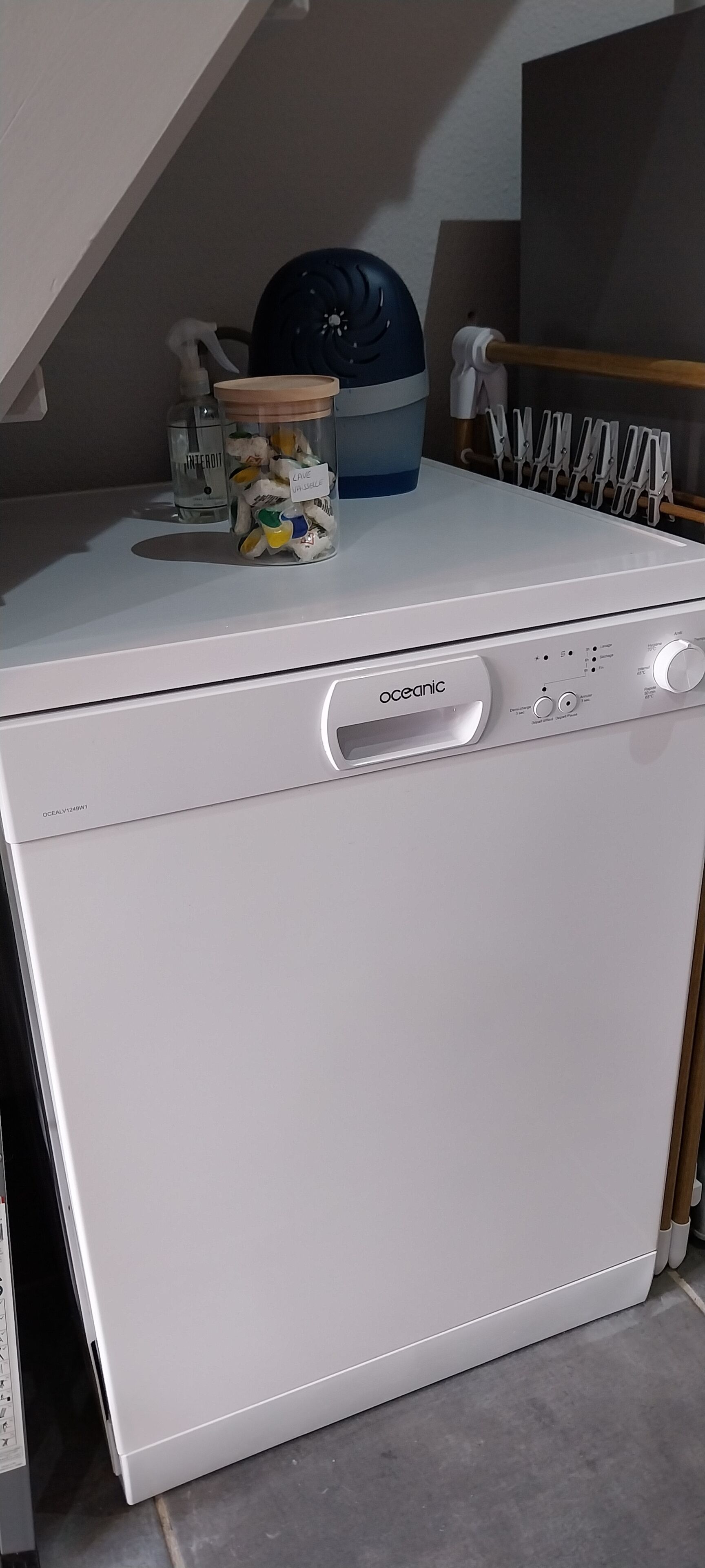 A white washing machine with a control panel, a blue container, and a bottle on top.