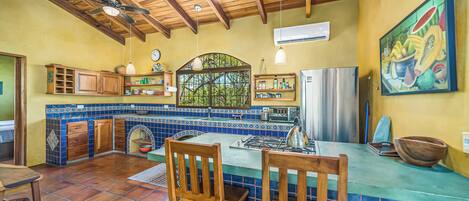A kitchen with wooden cabinets, a tiled backsplash, a central island, and hanging pendant lights.