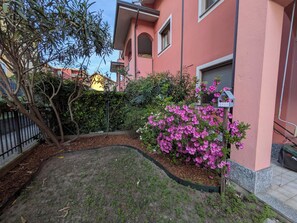 Un quartier résidentiel avec un bâtiment rose, un jardin parsemé de fleurs roses et un arbre.