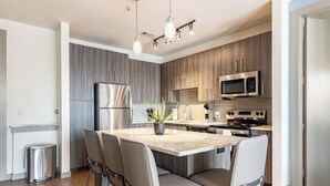 A modern kitchen with a central island, stainless steel appliances, and a potted plant. - Landing Furnished Apartments near UT Arlington (Arlington)