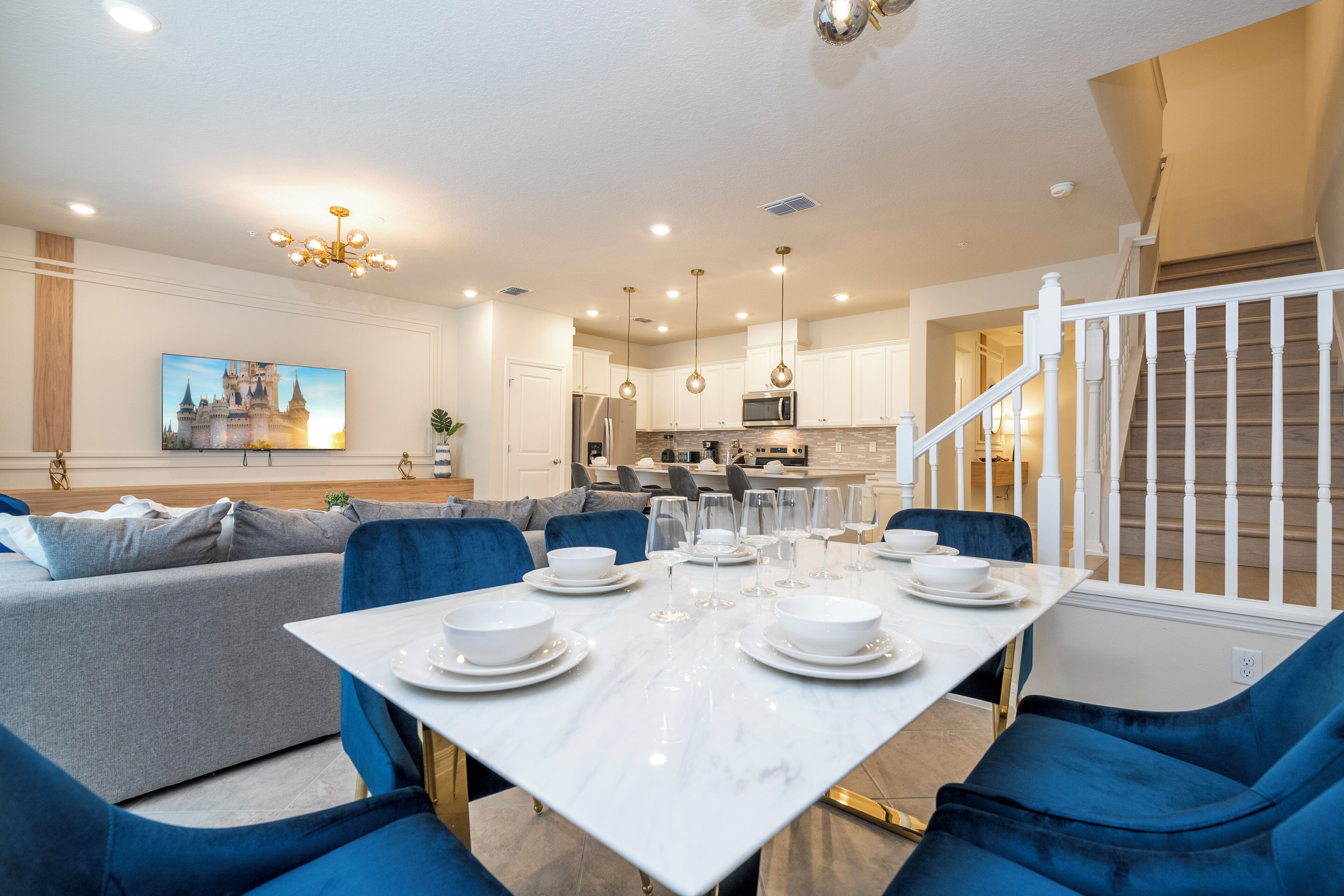 A modern dining area with a white table set for six, surrounded by blue chairs.