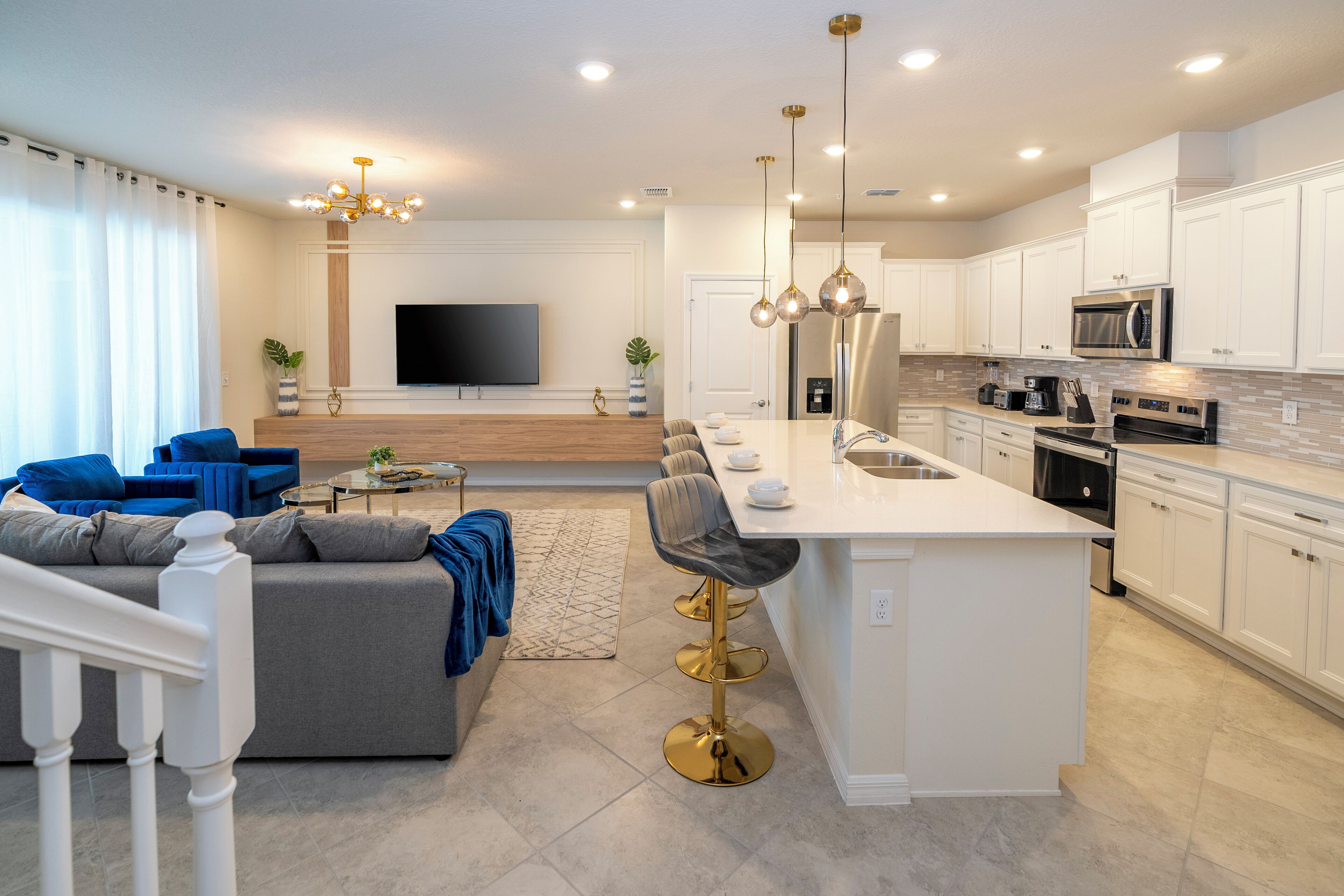 A modern kitchen with white cabinets, a central island, and a dining area with a sofa and chairs.