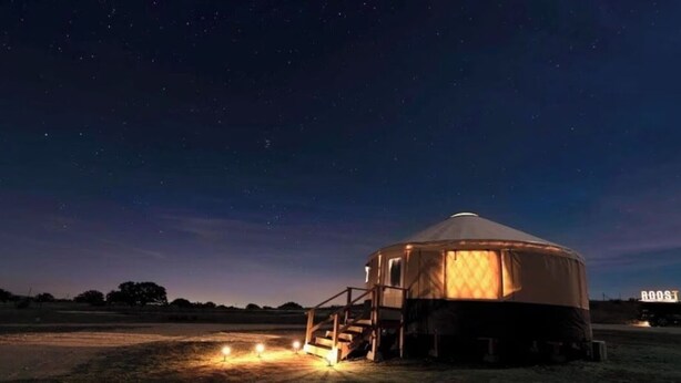 A yurt with a staircase leading to the entrance, surrounded by a grassy field under a starry night sky. - Glamping getaway Yurt with A/C in Johnson city (Johnson City)