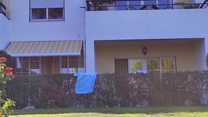 Een woongebouw met twee verdiepingen, een balkon, airconditioning en een gestreept zonnescherm.