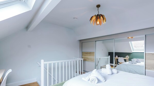 A bedroom with a skylight, a white bed, a white crib, and a mirror. - Trafalgar Road House (West Yorkshire)